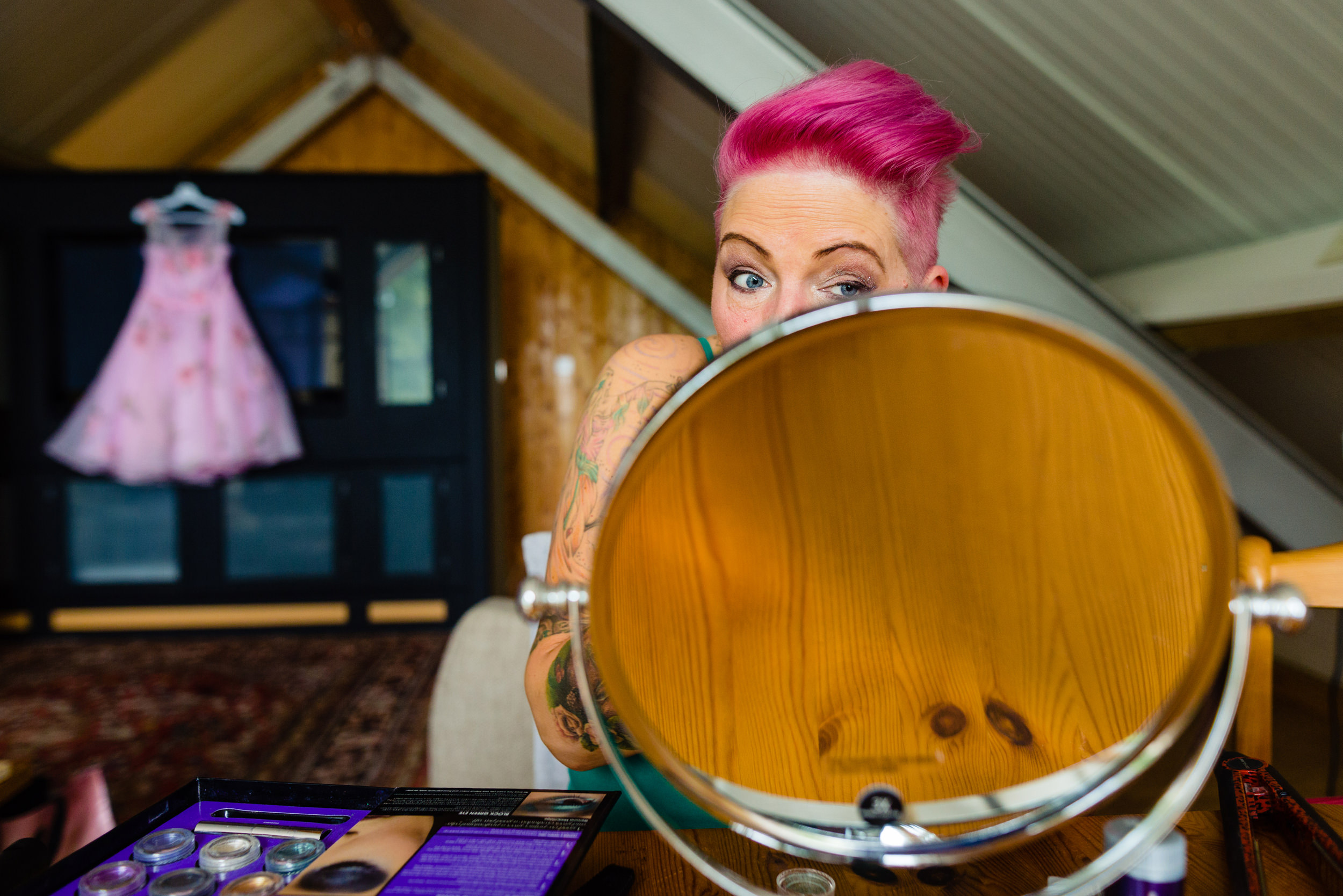 a pink-haired bride doing her make-up before the wedding.