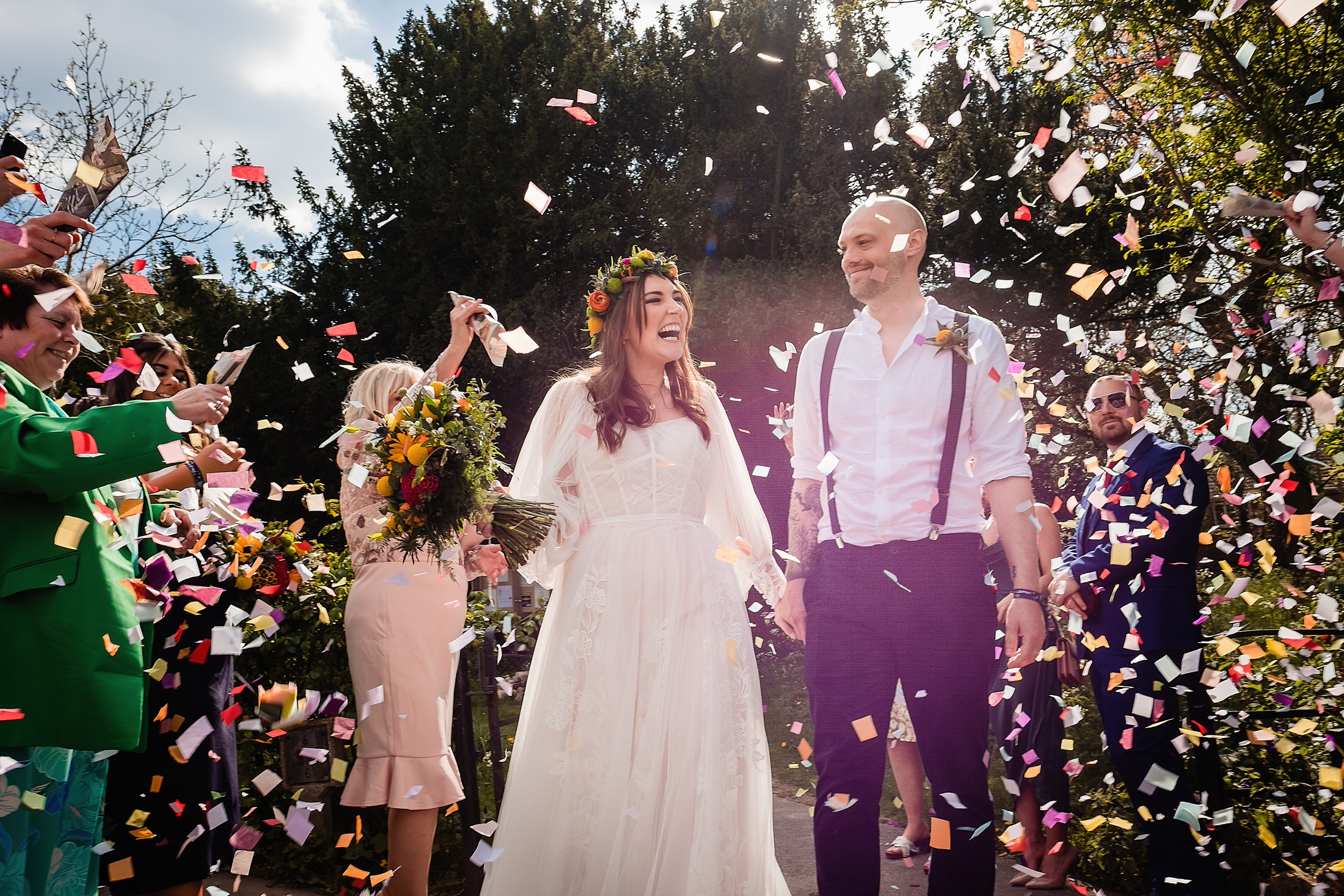 Bride and groom under a shower of coloured confetti - Lincolnshire wedding photography by Emma + Rich