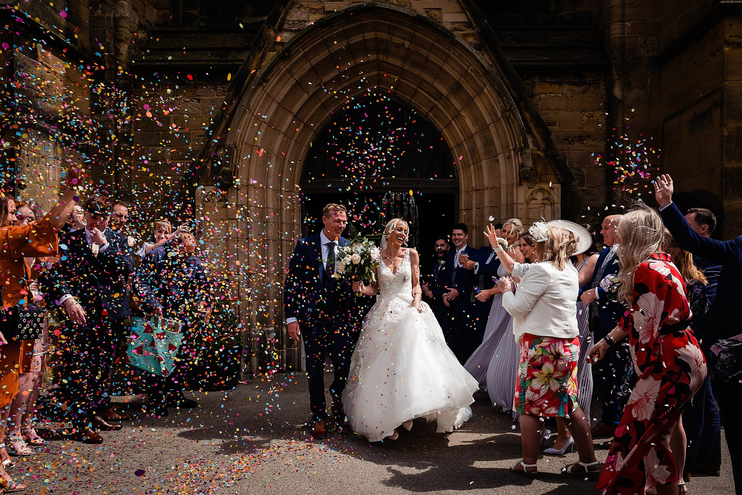 bride and groom exit the church and are covered in confetti. how to get the best confetti photos by emma and rich.